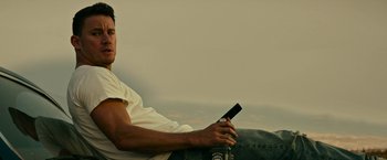 Movie still from “Dog” (2022), directed by Reid Carolin – A man sitting on the ground holding a cell phone; Medium shot, Low angle