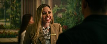 Movie still from “Dog” (2022), directed by Reid Carolin – A woman smiles brightly while wearing a jacket and tie; Close Up shot, Over the shoulder angle