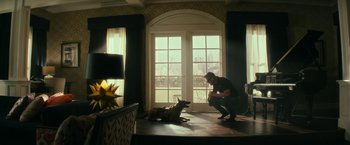 Movie still from “Dog” (2022), directed by Reid Carolin – A man kneeling down next to a dog in a living room; Wide shot, Low angle