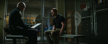 Movie still from “Dog” (2022), directed by Reid Carolin – A man sitting on top of a bench in front of a crowd; Medium shot, Over the shoulder angle