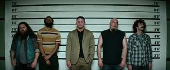 Movie still from “Dog” (2022), directed by Reid Carolin – Three men standing in front of a police line - up; Wide shot, Low angle