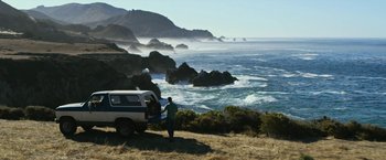 Movie still from “Dog” (2022), directed by Reid Carolin – A man standing next to a truck near the ocean; Extreme Wide shot, High angle