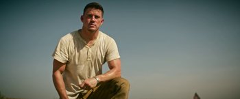 Movie still from “Dog” (2022), directed by Reid Carolin – A person crouching on the ground; Medium shot, Low angle