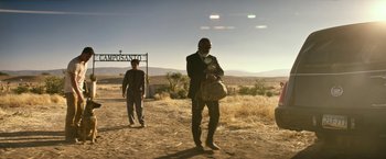 Movie still from “Dog” (2022), directed by Reid Carolin – Two men standing on a dirt road in front of a sign; Wide shot, Low angle