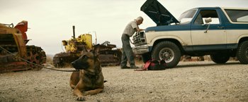 Movie still from “Dog” (2022), directed by Reid Carolin – A dog laying on the ground next to an open truck; Wide shot, Low angle