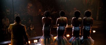 Movie still from “Dreamgirls” (2006), directed by Bill Condon – A group of women standing on a stage in front of an audience; Wide shot, Low angle