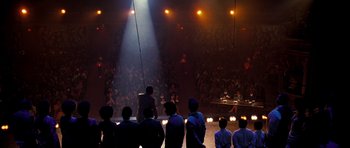 Movie still from “Dreamgirls” (2006), directed by Bill Condon – A group of people standing in front of an audience at night; Extreme Wide shot, High angle