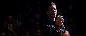 Movie still from “Dreamgirls” (2006), directed by Bill Condon – A man holding a tin can while standing in front of an audience; Close Up shot, High angle