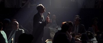 Movie still from “Dreamgirls” (2006), directed by Bill Condon – An older man in a black suit is holding a microphone; Medium shot, Low angle