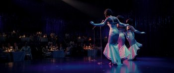 Movie still from “Dreamgirls” (2006), directed by Bill Condon – A couple of women on a stage with microphones; Wide shot, Over the shoulder angle
