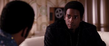 Movie still from “Dreamgirls” (2006), directed by Bill Condon – A man sitting on top of a couch in a living room; Close Up shot, Over the shoulder angle