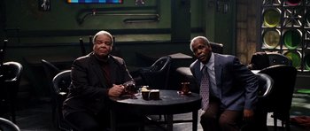 Movie still from “Dreamgirls” (2006), directed by Bill Condon – Two men sitting at a table with a cup of coffee; Medium shot, High angle