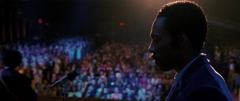 Movie still from “Dreamgirls” (2006), directed by Bill Condon – A man standing in front of a microphone in front of an audience; Close Up shot, Low angle