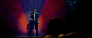 Movie still from “Dreamgirls” (2006), directed by Bill Condon – A man standing on a stage holding a microphone; Wide shot, Low angle
