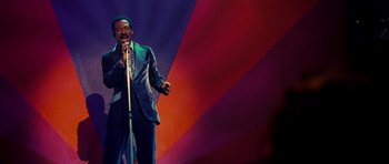 Movie still from “Dreamgirls” (2006), directed by Bill Condon – A man in a suit and tie holding a microphone; Medium shot, Low angle