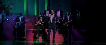 Movie still from “Dreamgirls” (2006), directed by Bill Condon – A man singing on stage with a band behind him; Wide shot, High angle