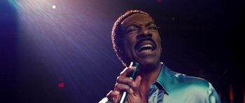 Movie still from “Dreamgirls” (2006), directed by Bill Condon – A person holding a microphone on a stage; Close Up shot, Low angle