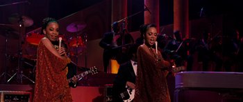 Movie still from “Dreamgirls” (2006), directed by Bill Condon – A woman holding a candle in front of an orchestra; Medium shot, Over the shoulder angle