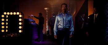 Movie still from “Dreamgirls” (2006), directed by Bill Condon – A man standing in front of an entertainment device; Medium shot, Low angle