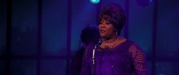 Movie still from “Dreamgirls” (2006), directed by Bill Condon – A woman in a purple dress singing into a microphone; Close Up shot, Over the shoulder angle