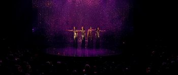 Movie still from “Dreamgirls” (2006), directed by Bill Condon – A group of women standing on top of a stage in front of a crowd of onlookers; Extreme Wide shot, High angle