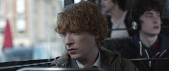 Movie still from “Frank” (2014), directed by Lenny Abrahamson – A man with red curly hair sitting on a bus; Close Up shot, Over the shoulder angle