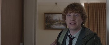 Movie still from “Frank” (2014), directed by Lenny Abrahamson – A man with a red curly hair and a green shirt and tie; Close Up shot, Over the shoulder angle