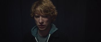Movie still from “Frank” (2014), directed by Lenny Abrahamson – A man with blonde hair and a blue hoodie; Close Up shot, Over the shoulder angle