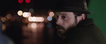 Movie still from “Frank” (2014), directed by Lenny Abrahamson – A man with a beard and a hat is looking at the camera; Close Up shot, Over the shoulder angle