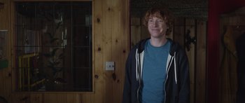 Movie still from “Frank” (2014), directed by Lenny Abrahamson – A man standing in front of a wooden wall; Medium shot, Over the shoulder angle