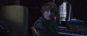 Movie still from “Frank” (2014), directed by Lenny Abrahamson – A man sitting at a table in front of a window; Close Up shot, Over the shoulder angle