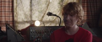 Movie still from “Frank” (2014), directed by Lenny Abrahamson – A man sitting in front of an electrical device; Close Up shot, Over the shoulder angle