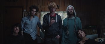 Movie still from “Frank” (2014), directed by Lenny Abrahamson – A group of young men standing next to each other in a room; Medium shot, Low angle