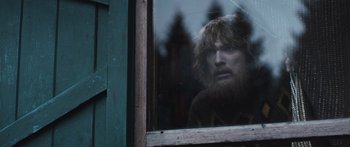 Movie still from “Frank” (2014), directed by Lenny Abrahamson – A man with a beard looking out of a window; Medium shot, Over the shoulder angle