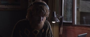 Movie still from “Frank” (2014), directed by Lenny Abrahamson – A man with a beard wearing headphones and a sweater; Close Up shot, Low angle