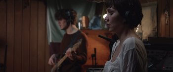 Movie still from “Frank” (2014), directed by Lenny Abrahamson – Two people are playing a guitar and a microphone; Medium shot, Over the shoulder angle
