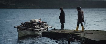 Movie still from “Frank” (2014), directed by Lenny Abrahamson – A man standing on a pier next to a boat; Wide shot, Over the shoulder angle