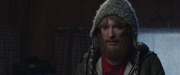 Movie still from “Frank” (2014), directed by Lenny Abrahamson – A man with long red hair and a beard wearing a hat; Close Up shot, Over the shoulder angle