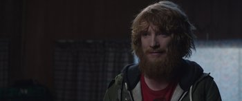 Movie still from “Frank” (2014), directed by Lenny Abrahamson – A man with a long beard and a red shirt; Close Up shot, Over the shoulder angle