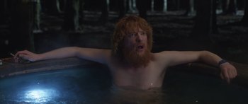 Movie still from “Frank” (2014), directed by Lenny Abrahamson – A man with a red beard is in a pool of water; Medium shot, Over the shoulder angle