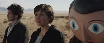 Movie still from “Frank” (2014), directed by Lenny Abrahamson – A woman standing next to another woman in the desert; Close Up shot, Over the shoulder angle