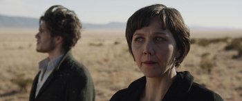 Movie still from “Frank” (2014), directed by Lenny Abrahamson – A woman standing next to a man in the desert; Close Up shot, Over the shoulder angle
