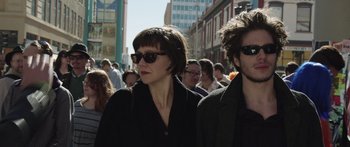 Movie still from “Frank” (2014), directed by Lenny Abrahamson – A woman and a man are walking down the street; Close Up shot, Low angle