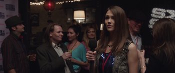 Movie still from “Frank” (2014), directed by Lenny Abrahamson – A group of people standing in a room with microphones; Close Up shot, Over the shoulder angle