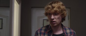 Movie still from “Frank” (2014), directed by Lenny Abrahamson – A man with red hair and a checkered shirt looking to his left; Close Up shot, Over the shoulder angle