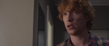 Movie still from “Frank” (2014), directed by Lenny Abrahamson – A person wearing a plaid shirt; Close Up shot, Over the shoulder angle