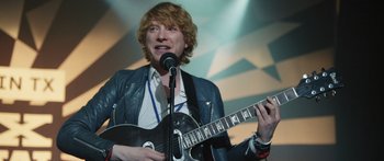 A man holding a black guitar and a microphone