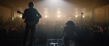 Movie still from “Frank” (2014), directed by Lenny Abrahamson – A crowd of people in a room with lights on; Wide shot, Low angle