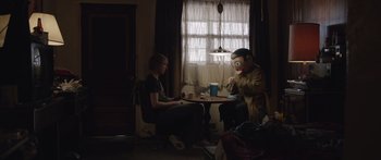 Movie still from “Frank” (2014), directed by Lenny Abrahamson – A man sitting at a table in front of another man; Medium shot, Over the shoulder angle