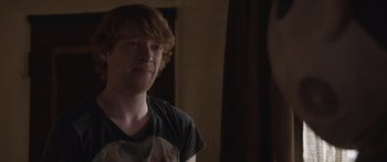Movie still from “Frank” (2014), directed by Lenny Abrahamson – A man with red hair is looking at the camera; Close Up shot, Over the shoulder angle